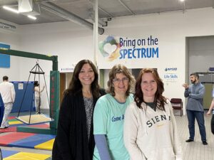 image of three women standing behind wall logo – Bring on the Spectrum