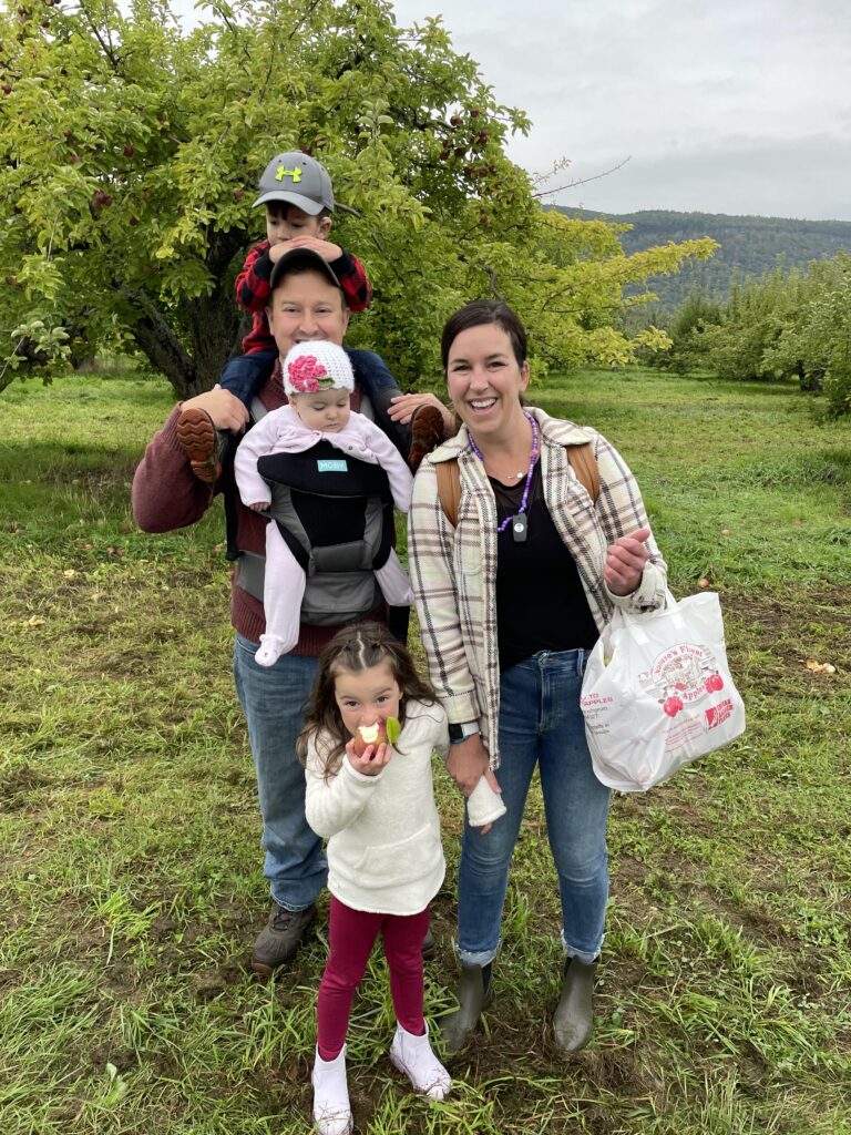 Family posing for picture holding a bag of apples